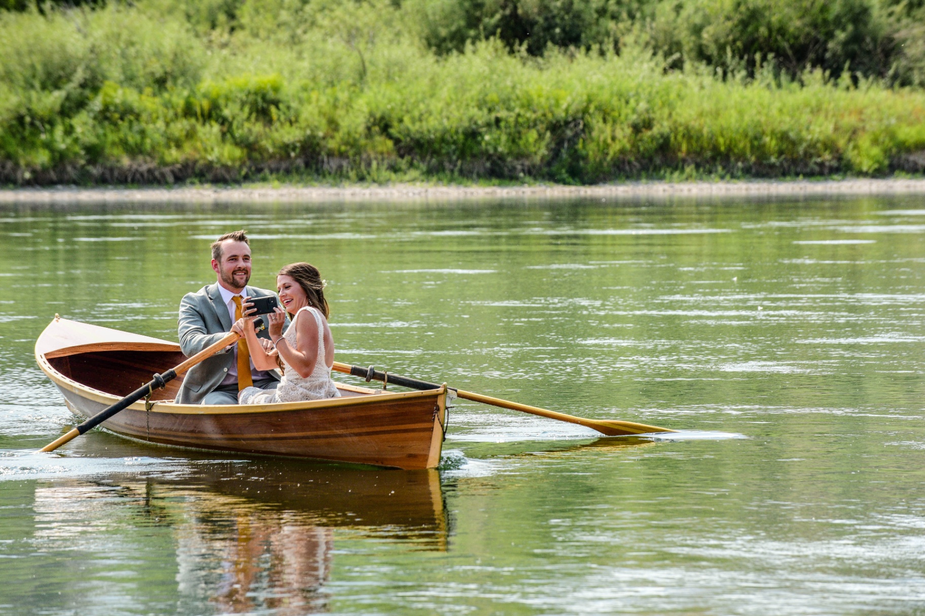 Bride and groom in a wooden rowboat on the river